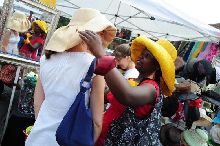 A vendor assists a woman in trying on hats on at Eastern Market in Washington, D.C.  Established in 1873, it is one of the few public markets left in Washington.